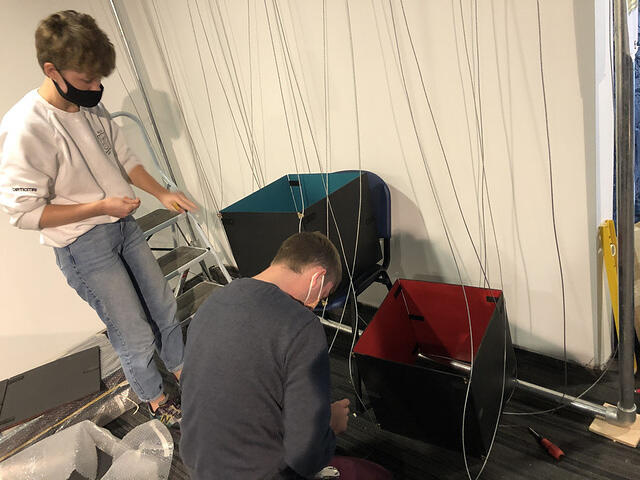 Two students assembling a coloured panel structure